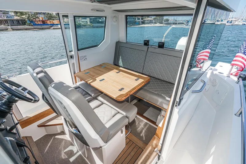 Slide: The Image of Interior of 2019 Axopar 28 CABIN boat with seating and table, docked by the water. - 8