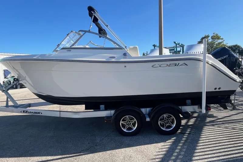 Slide: The Image of 2023 Cobia 220 Dual Console boat on trailer, side view, clear sky background. - 4