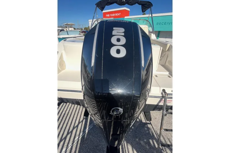 Slide: The Image of 2023 Cobia 220 Dual Console with Mercury 200 outboard engine, docked under clear skies. - 6