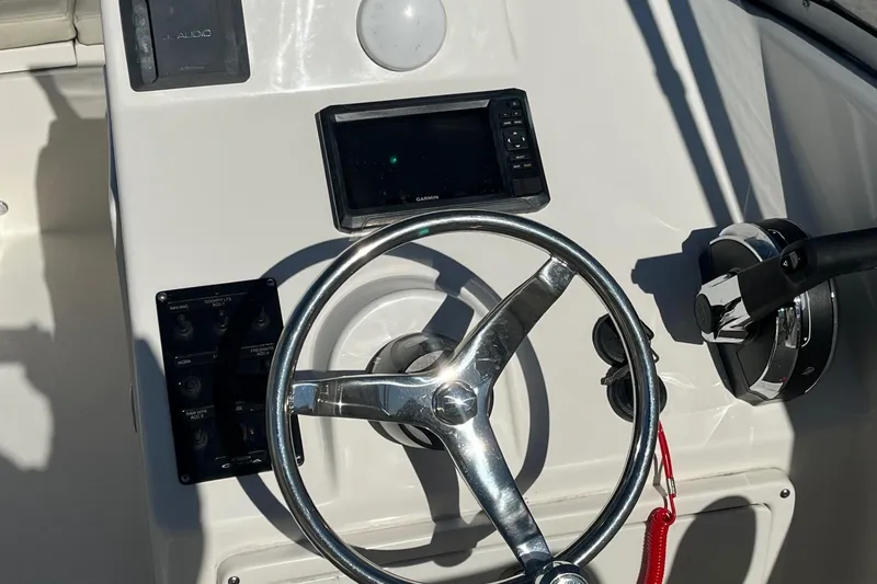 Slide: The Image of 2023 Cobia 220 Dual Console boat helm with steering wheel and controls. - 7