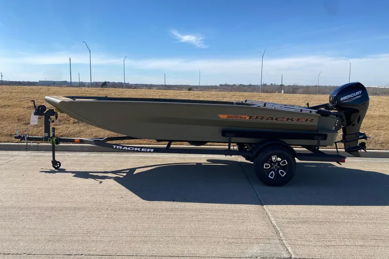 The Image of 2026 Tracker Grizzly 1756 T Marsh boat on trailer, parked on concrete, clear sky background. - 0