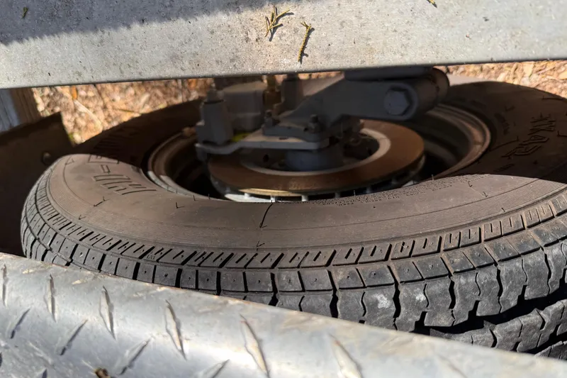 Slide: The Image of Close-up of a tire and brake system on a 2016 Robalo R247 Dual Console trailer. - 17