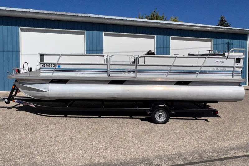 Slide: The Image of 1992 Northwoods Fun Deluxe Pontoon boat on trailer, parked outside blue building. - 22