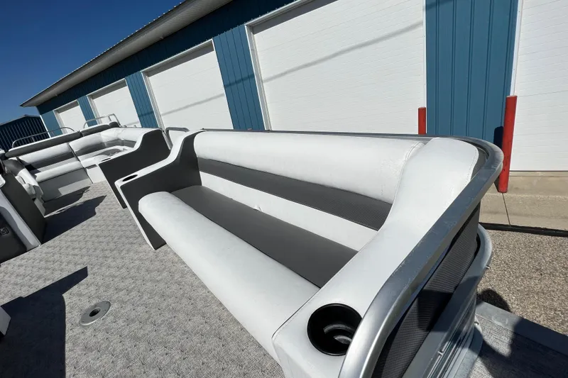 Slide: The Image of 1992 Northwoods Fun Deluxe Pontoon with gray seating, docked near blue and white building. - 8