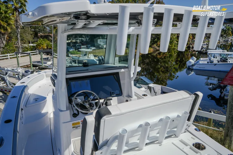 Slide: The Image of 2025 Blackfin 262 HB boat cockpit with steering wheel and rod holders, docked near water. - 17