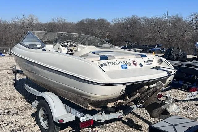Slide: The Image of 2011 Stingray 185 LS/LX boat on trailer, parked outdoors on gravel. - 2
