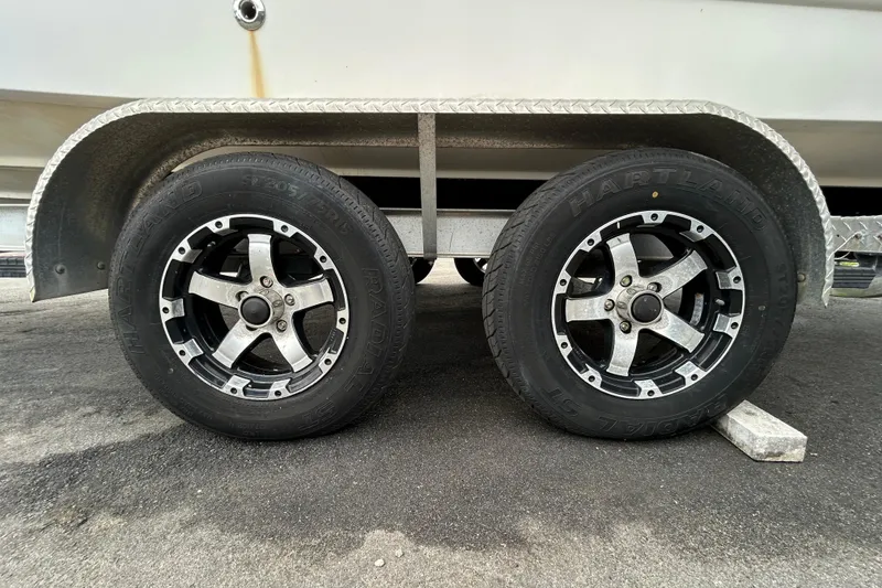 Slide: The Image of Trailer wheels of a 2006 Chaparral Sunesta 236 boat on pavement. - 104