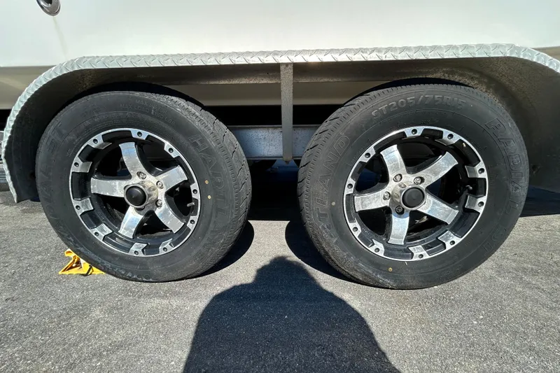Slide: The Image of Trailer wheels of a 2006 Chaparral Sunesta 236 boat on pavement. - 26