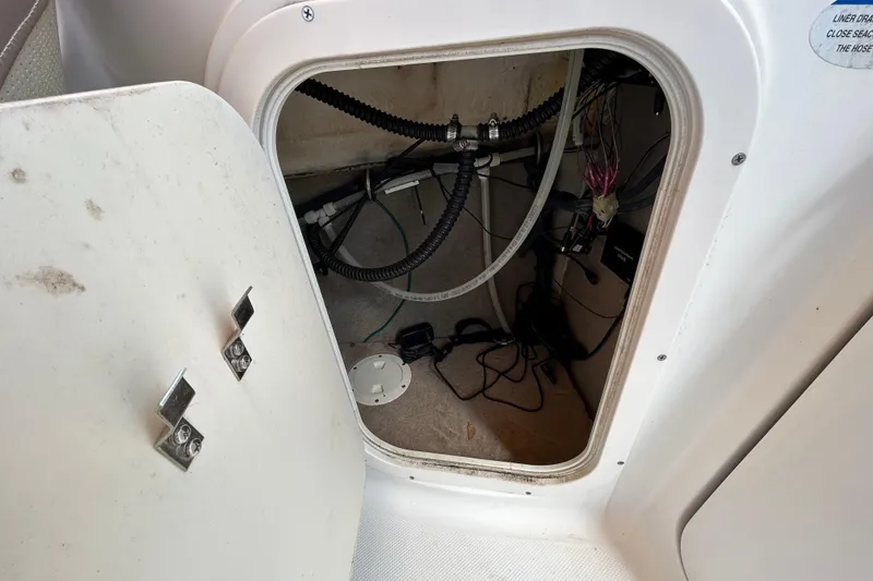 Slide: The Image of Open storage compartment in 2006 Chaparral Sunesta 236 boat, showing wiring and hoses. - 51