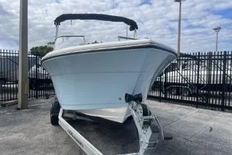 Slide: The Image of 2023 Cobia 220 Dual Console boat on trailer, parked outdoors under cloudy sky. - 3
