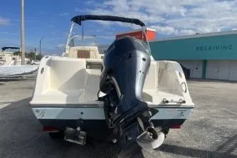 Slide: The Image of 2023 Cobia 220 Dual Console boat with outboard motor, parked outdoors. - 6