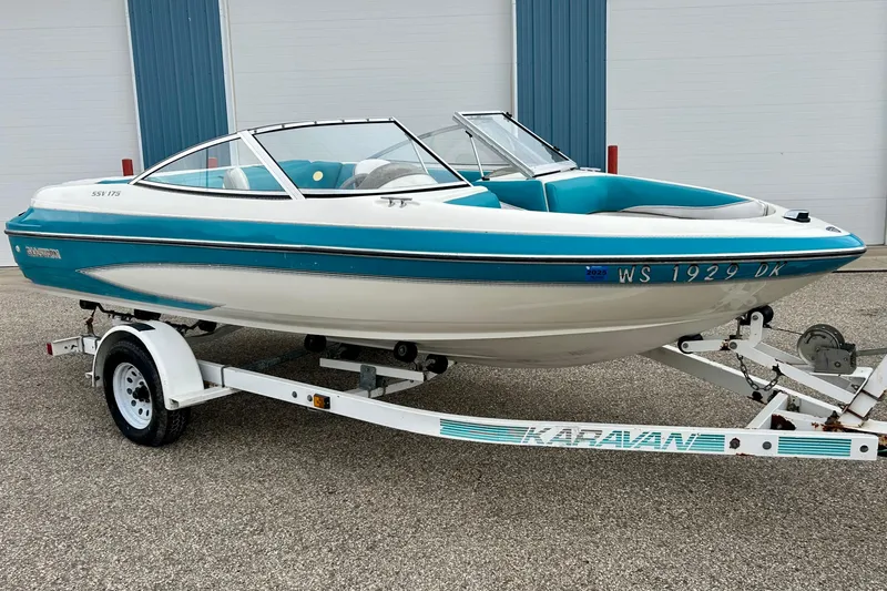 The Image of 1993 Glastron SSV 175 boat on trailer, teal and white design, parked outdoors. - 0
