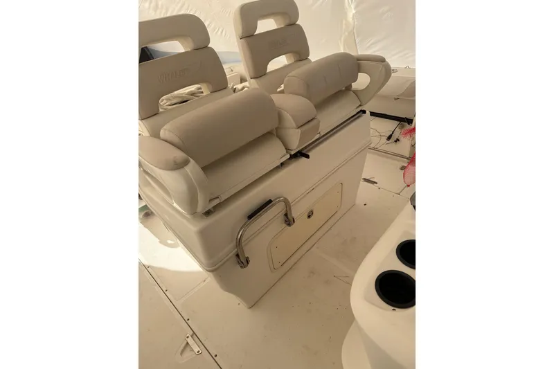 Slide: The Image of 2004 Boston Whaler 320 Outrage boat seating area with cushioned seats and storage compartment. - 10