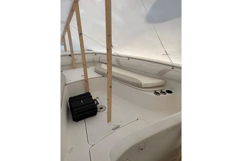 Slide: The Image of 2004 Boston Whaler 320 Outrage boat interior under cover, featuring seating and storage. - 4