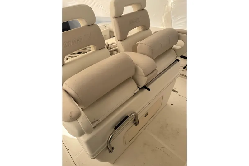 Slide: The Image of 2004 Boston Whaler 320 Outrage boat seating, featuring cushioned beige seats and storage compartment. - 8