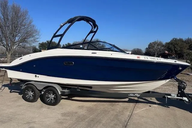 The Image of 2024 Sea Ray SPX 210 boat on trailer, blue and white design, parked outdoors. - 0