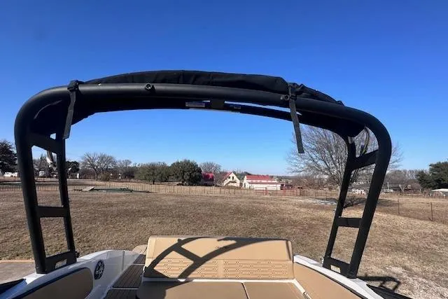 Slide: The Image of 2024 Sea Ray SPX 210 boat with black wakeboard tower, parked on grassy field. - 19