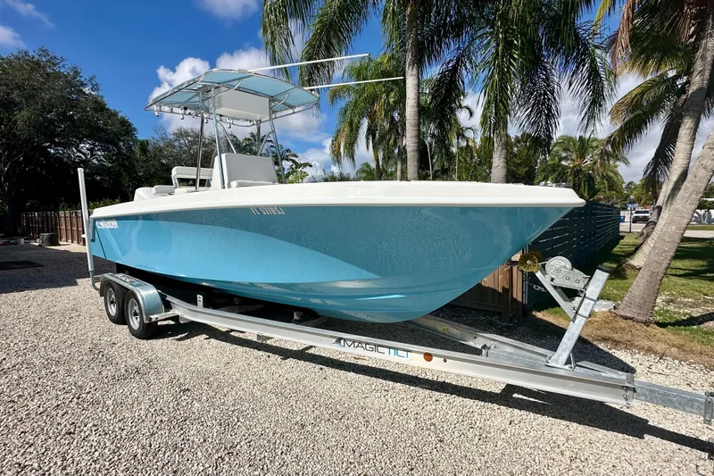 Slide: The Image of 2001 Contender 23 Open boat on trailer, parked outdoors with palm trees in background. - 1