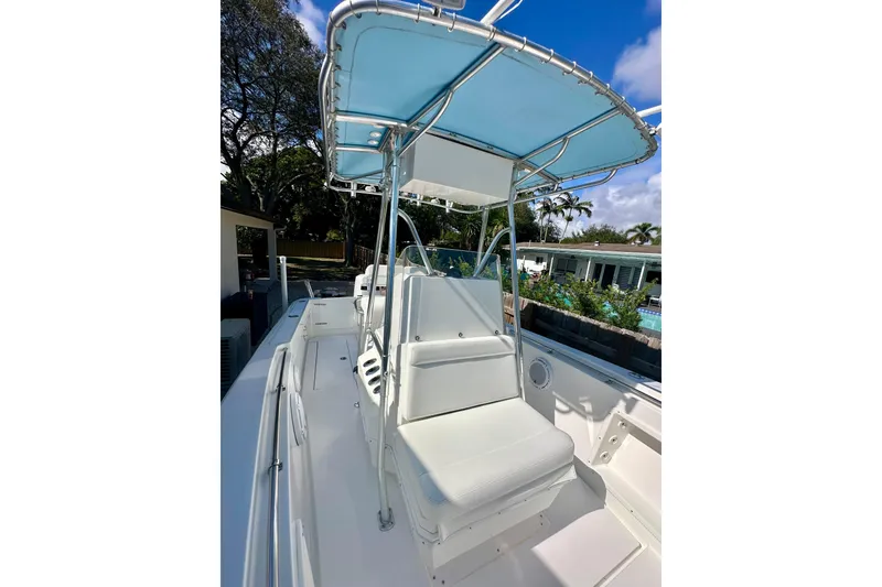 Slide: The Image of 2001 Contender 23 Open boat deck with steering console and seating, surrounded by lush greenery. - 41