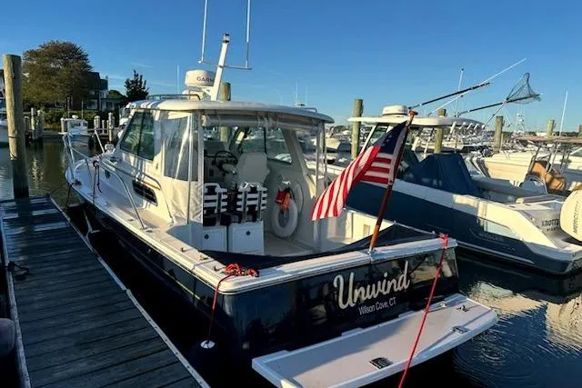 Slide: The Image of 2007 Back Cove 29 boat named "Unwind" docked at a marina with American flag. - 7