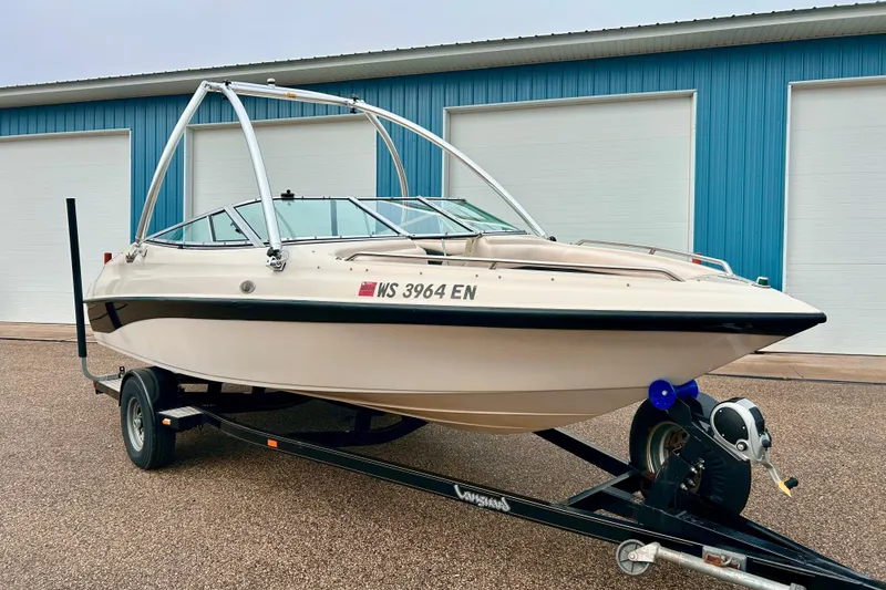 Slide: The Image of 1995 Crownline 202 BR boat on trailer, parked near blue building. - 2