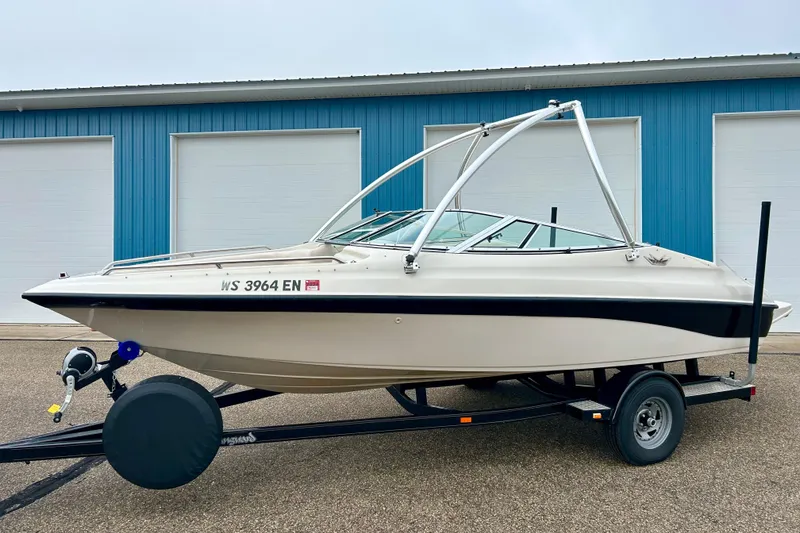 Slide: The Image of 1995 Crownline 202 BR boat on trailer, parked outside blue building. - 22