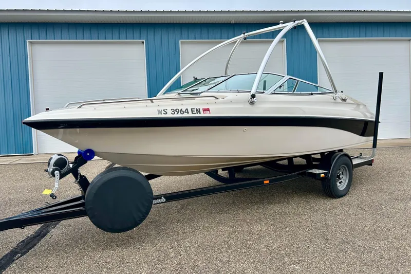 Slide: The Image of 1995 Crownline 202 BR boat on trailer, parked outside blue building. - 23