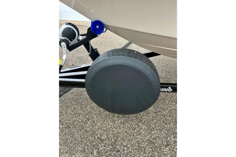 Slide: The Image of 1995 Crownline 202 BR boat trailer with covered wheel on asphalt surface. - 25