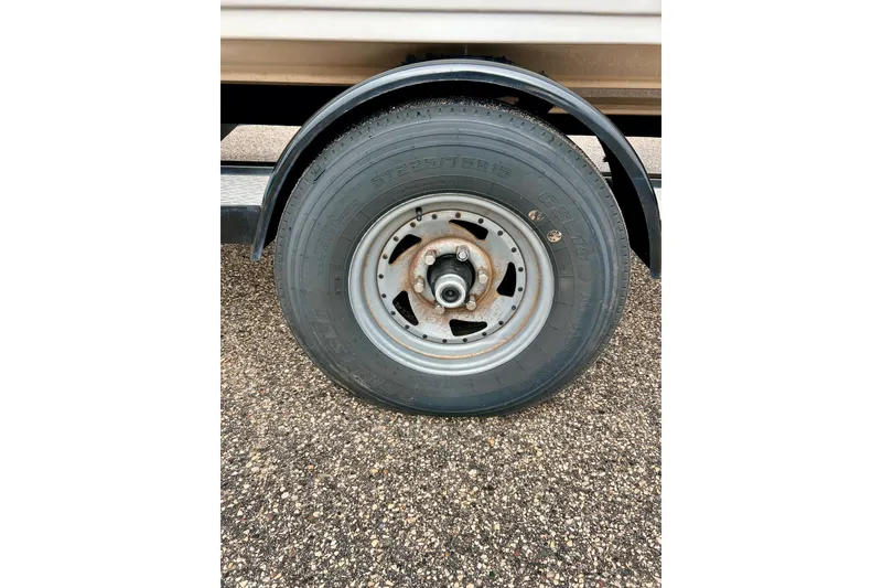 Slide: The Image of 1995 Crownline 202 BR trailer wheel on textured pavement. - 56