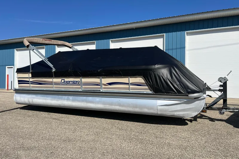 Slide: The Image of 2001 Premier 250 Grand Majestic pontoon boat with cover, parked outside blue building. - 3