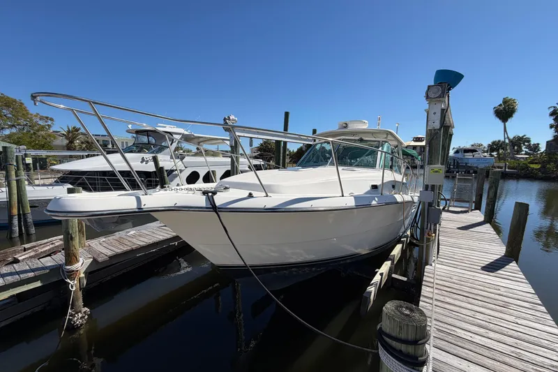 Slide: The Image of 2001 Pursuit 3000 Express boat docked at marina under clear blue sky. - 2