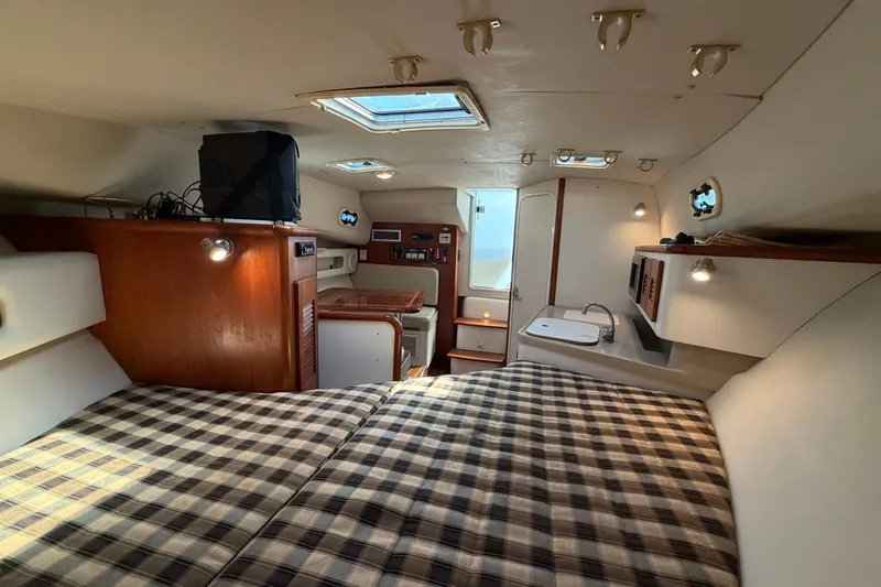 Slide: The Image of Interior of 2001 Pursuit 3000 Express boat with cozy cabin and plaid bedding. - 27