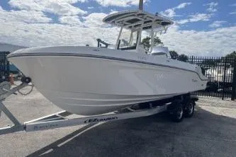 Slide: The Image of 2023 Trophy T24 CC boat on trailer, parked outdoors under a partly cloudy sky. - 4