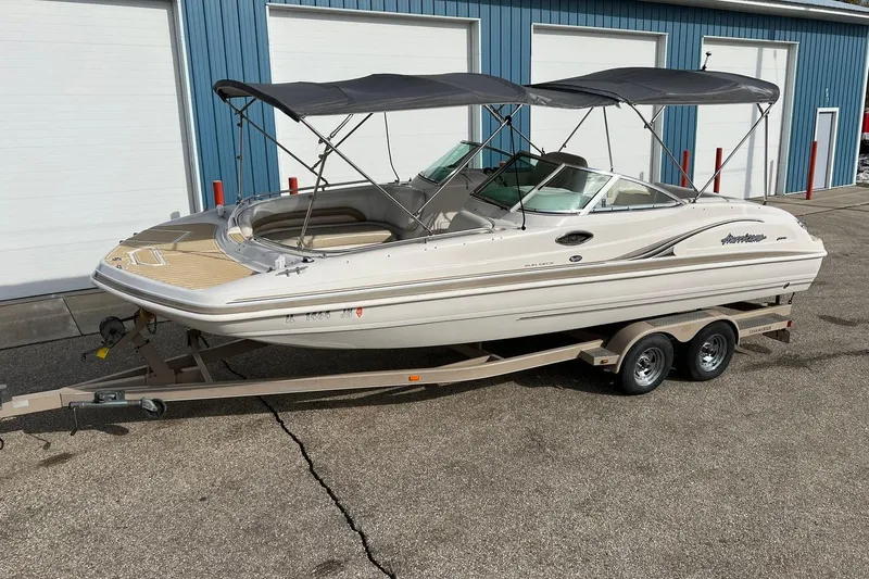 Slide: The Image of 2001 Hurricane SunDeck 237 OB boat on trailer, parked outside blue building. - 1