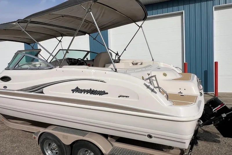 Slide: The Image of 2001 Hurricane SunDeck 237 OB boat with canopy, parked on a trailer near a blue building. - 18