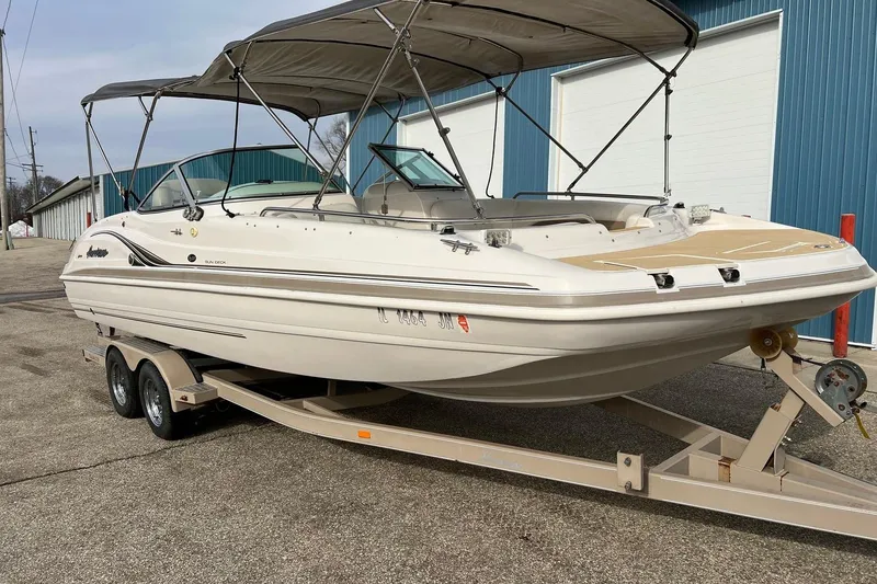 Slide: The Image of 2001 Hurricane SunDeck 237 OB boat on trailer, parked near blue building. - 19