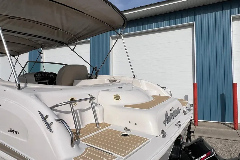 Slide: The Image of 2001 Hurricane SunDeck 237 OB boat with canopy, parked near blue building. - 3