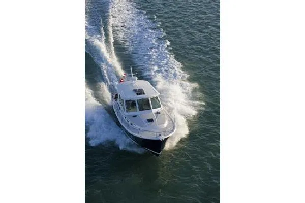Slide: The Image of 2010 Back Cove 37 boat cruising on calm waters with scenic mountain backdrop. - 3