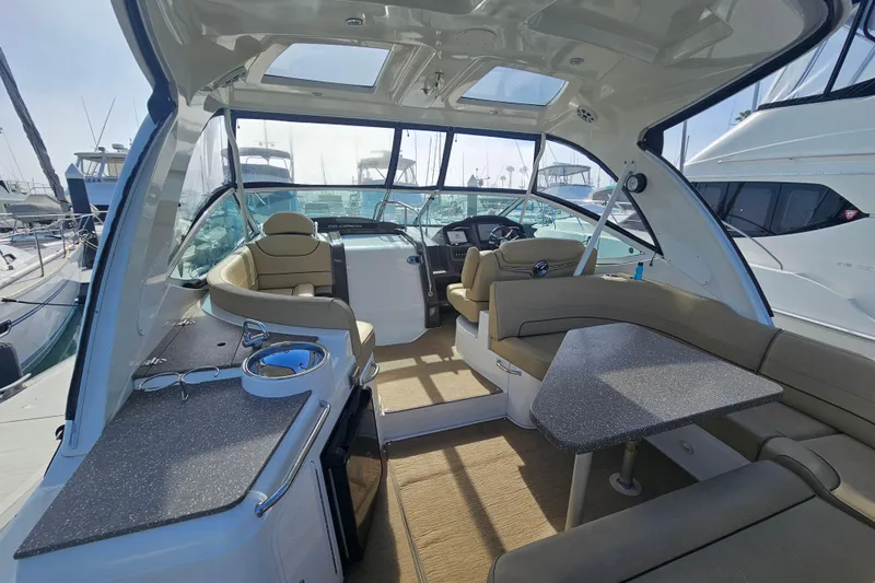 Slide: The Image of 2012 Cruisers Yachts 350 Express interior with seating, table, and helm in marina setting. - 15