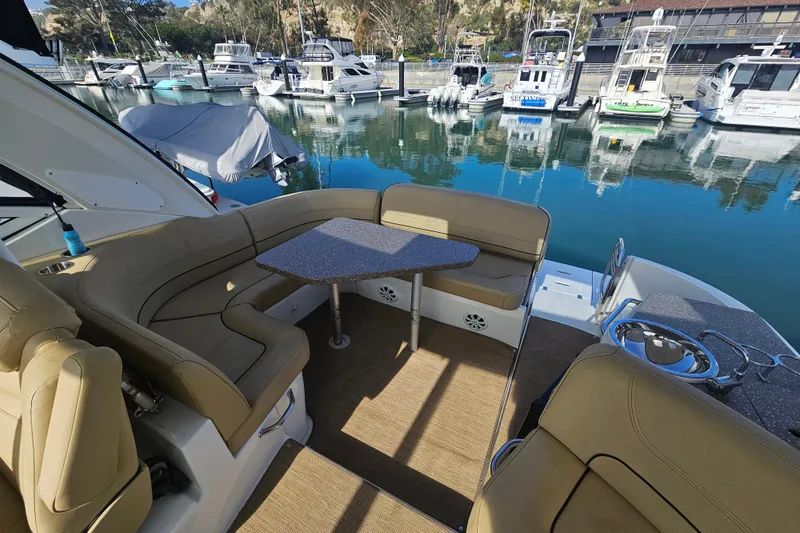 Slide: The Image of 2012 Cruisers Yachts 350 Express interior with seating and table, docked at marina. - 19