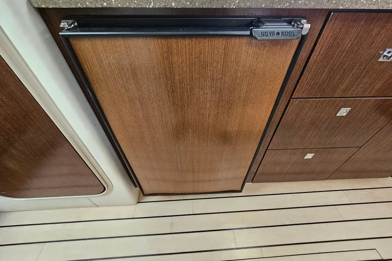 Slide: The Image of 2012 Cruisers Yachts 350 Express interior with wood paneling and Nova Kool fridge. - 26