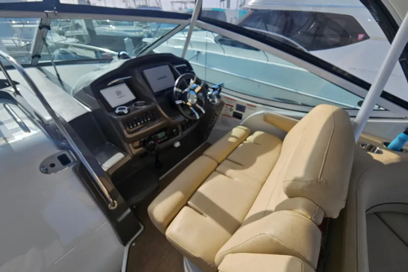 Slide: The Image of 2012 Cruisers Yachts 350 Express helm with beige seating and modern controls. - 8