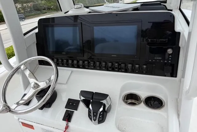 Slide: The Image of 2025 Sea Hunt Ultra 265 SE boat dashboard with dual screens and steering wheel. - 12