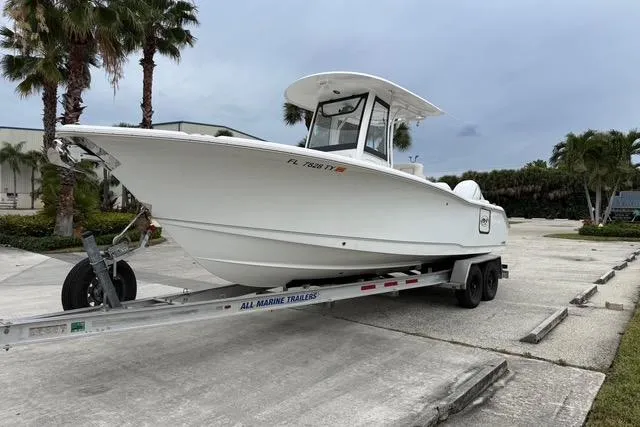 Slide: The Image of 2025 Sea Hunt Ultra 265 SE boat on trailer, parked outdoors with palm trees. - 3