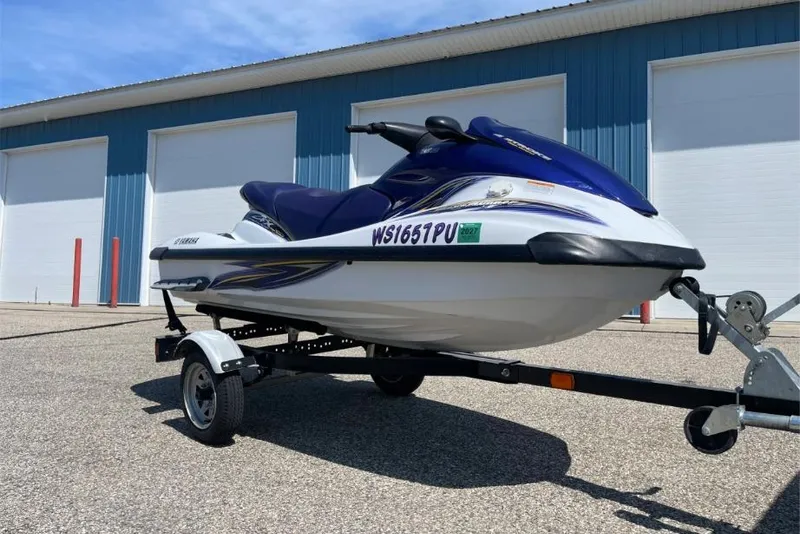 Slide: The Image of 2004 Yamaha FX 1000 jet ski on trailer, parked outside blue building. - 2