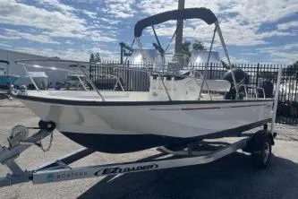 Slide: The Image of 2022 Boston Whaler 170 Montauk boat on trailer, parked outdoors under a cloudy sky. - 4