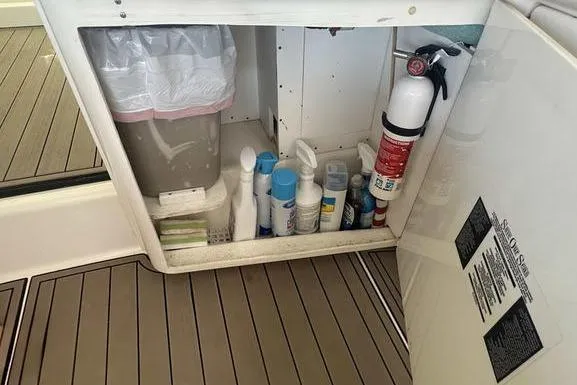 Slide: The Image of Storage compartment on a 2010 Sea Ray 450 Sundancer with cleaning supplies and fire extinguisher. - 15