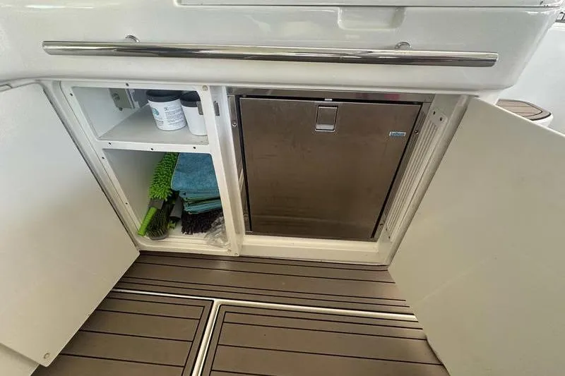 Slide: The Image of Open storage compartment on 2010 Sea Ray 450 Sundancer boat with cleaning supplies and mini fridge. - 16