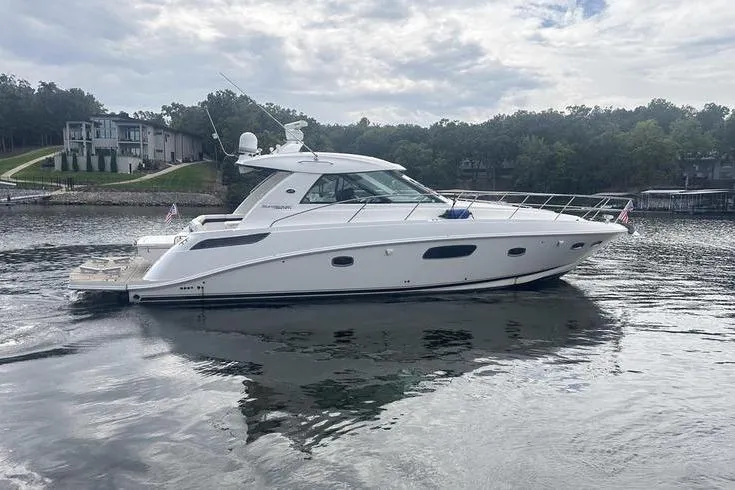 Slide: The Image of 2010 Sea Ray 450 Sundancer yacht on a serene lake with lush surroundings. - 4