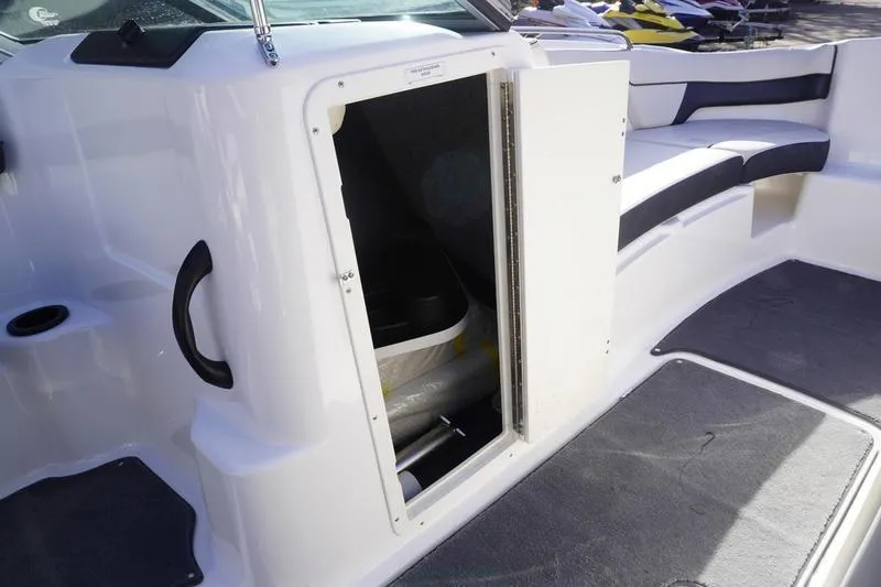 Slide: The Image of 2015 Yamaha Boats SX210 interior storage compartment with open door, showcasing seating and flooring. - 13